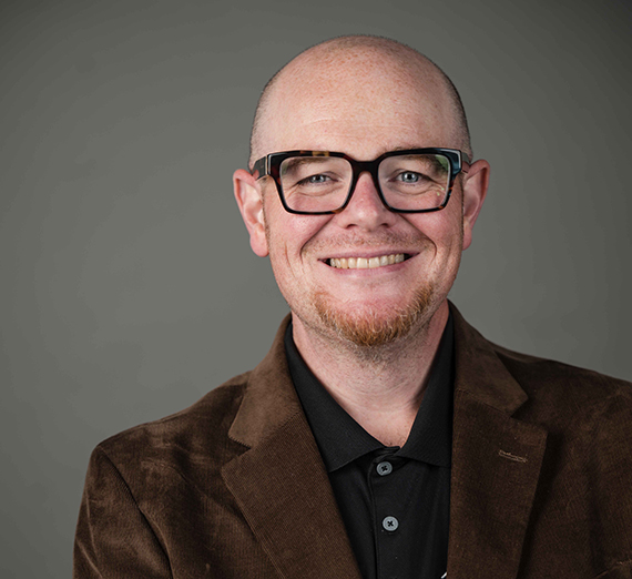 졸업복을 입은 남성이 "고잔가 대학교"라고 쓰인 학위증을 들어 올리고 있다.